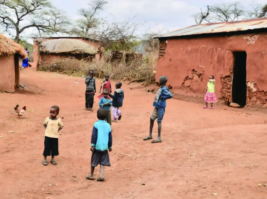 children gathered in front of bomas at a local village in tanzania
