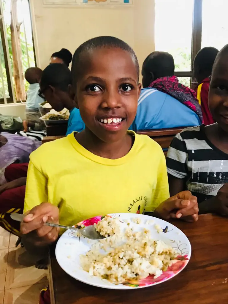 a maasai girl eating nutritious, farm fresh food harvested from our eco farm