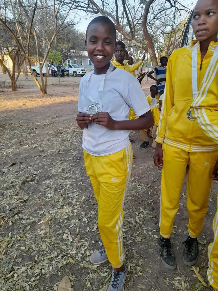 Maria displaying her national title medal in the 100-meter race.
Maria and Upendo at their homecoming celebration.