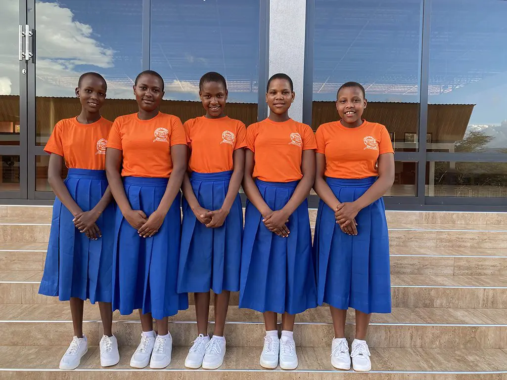 5 MGRC girls in their uniforms standing in row outside their school