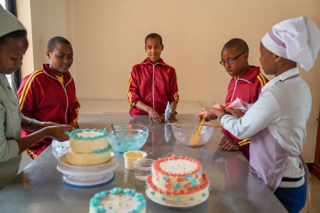Several maasai girls being tought how to bake a cake by one of our resident cooks.