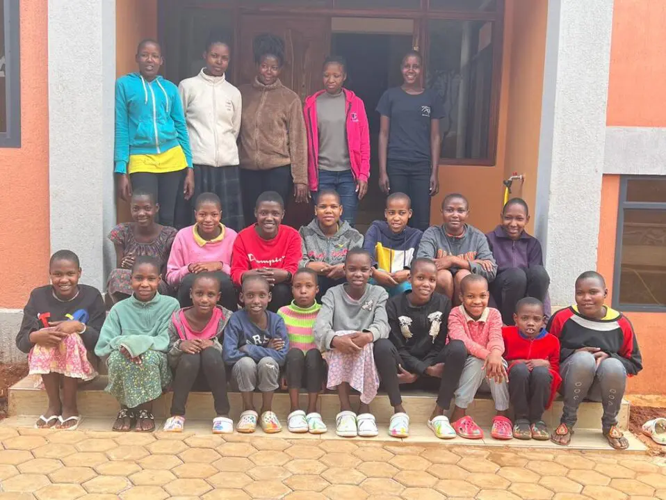 MGRC girls sitting outside their new home with their house mothers
