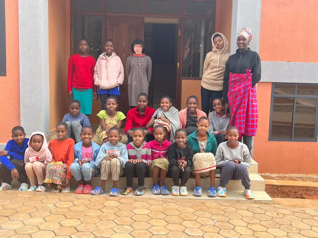 MGRC girls sitting outside their new home with their house mothers