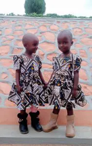 The twins standing together in matching dresses have started school.