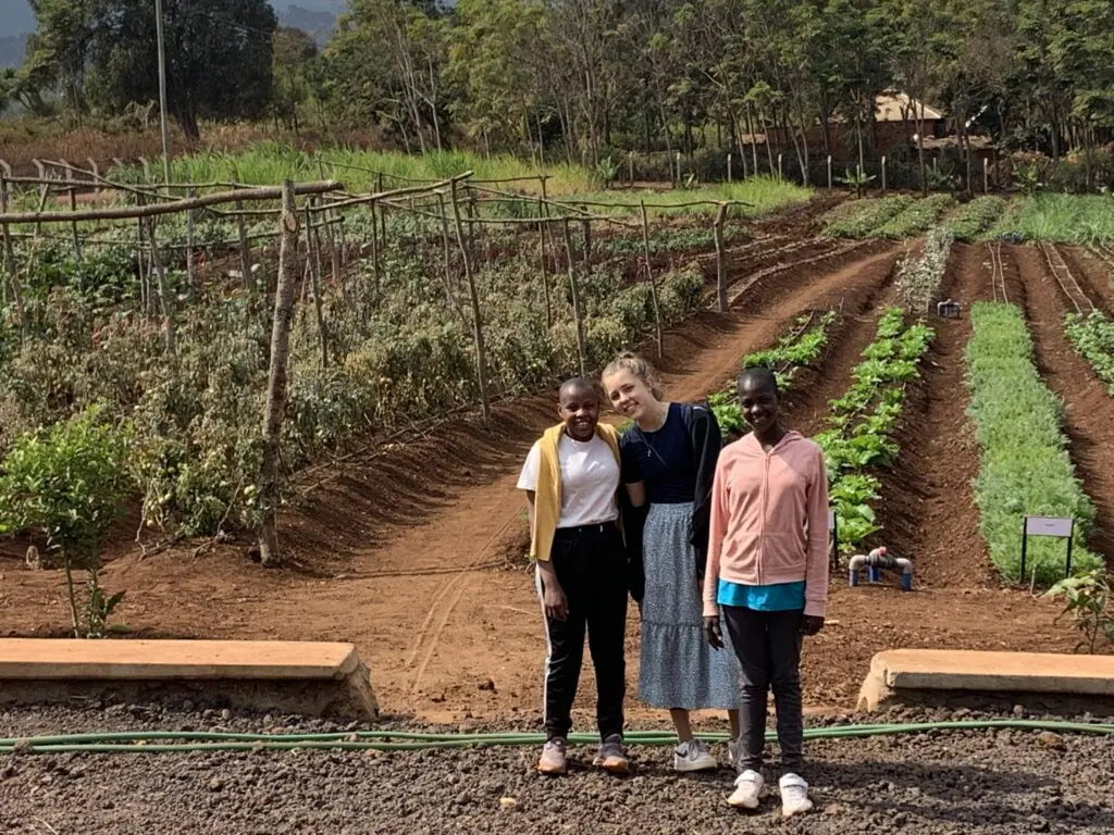life of a volunteer, young volunteer touring the ecoFarm with two Maasai girls. 