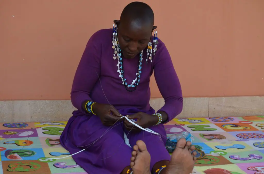 Coco sitting while crafting traditional bead making