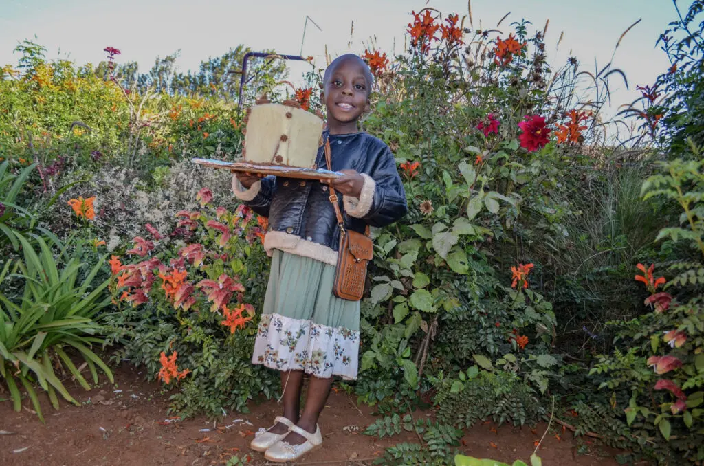 Smiling child holding a cake is perk of sponsoring a girl
