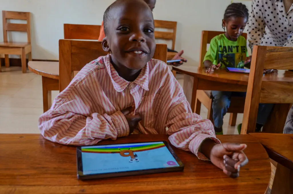 Child smiling with tablet in classroom