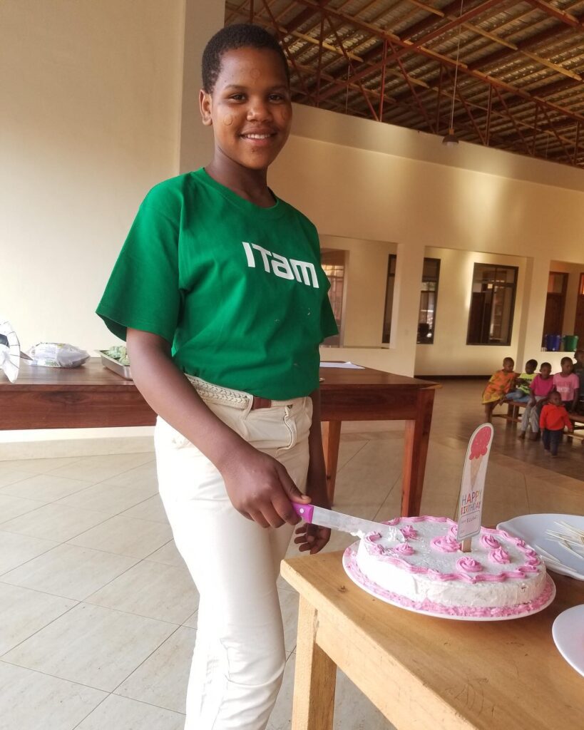 maasai girl standing in front of the cake she made during vocational studies.