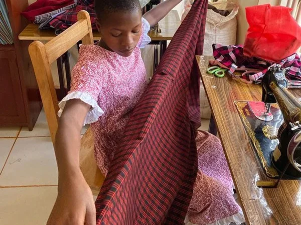 a young African girl learning to sew as part of our social enterprise