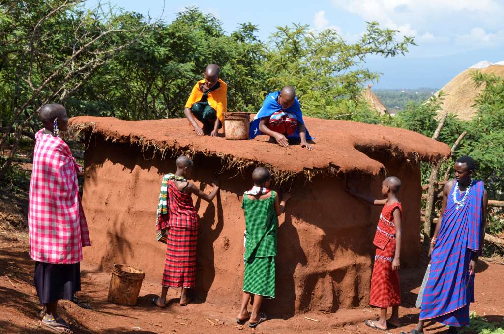 Maasai girls building a boma under the guidance of maasai elders as of their maasai culture curriculum
