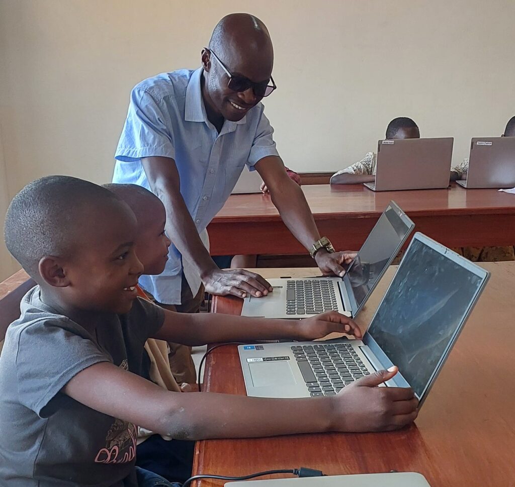 Yona Lumliko helping young Maasai girls use a computer for the first time at MGRC