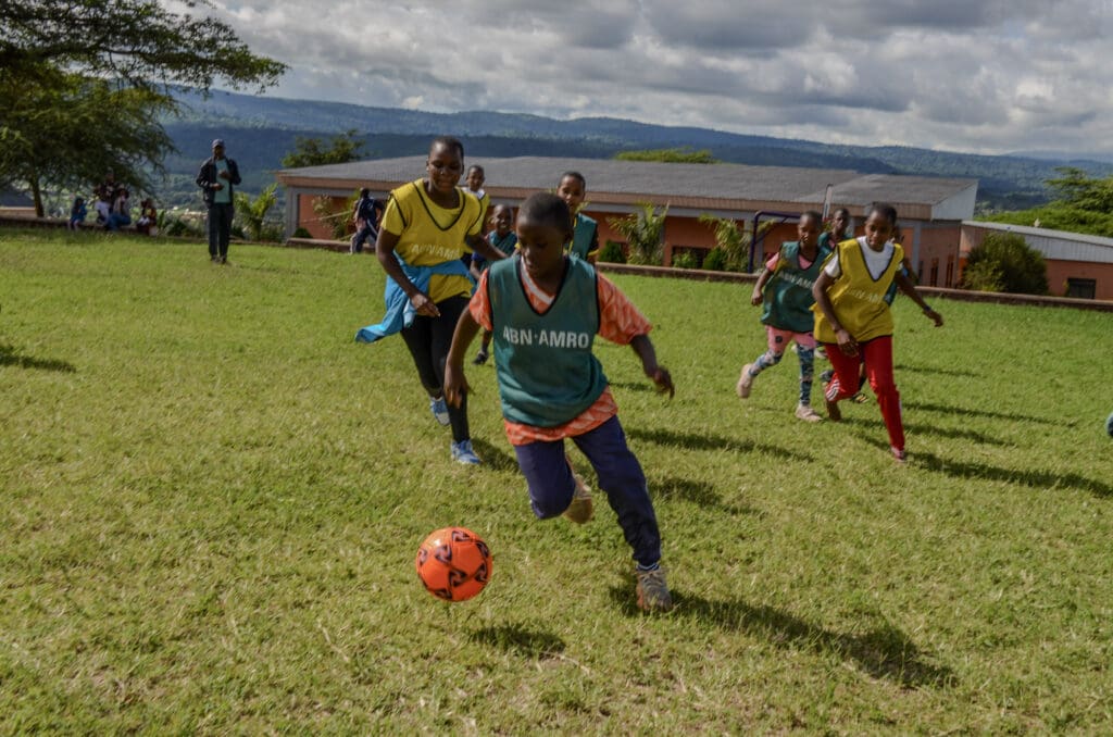 Girls playing soccer on green sports field at our ecoVillage